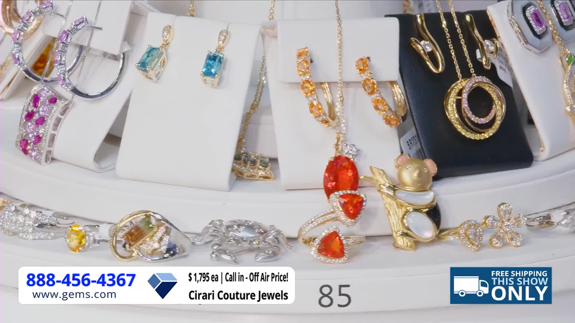 A rotating display of jewelry sparkles under bright lights. The Gem Shopping Network is promoting Cirari Couture Jewels, with a phone number and price displayed at the bottom.

