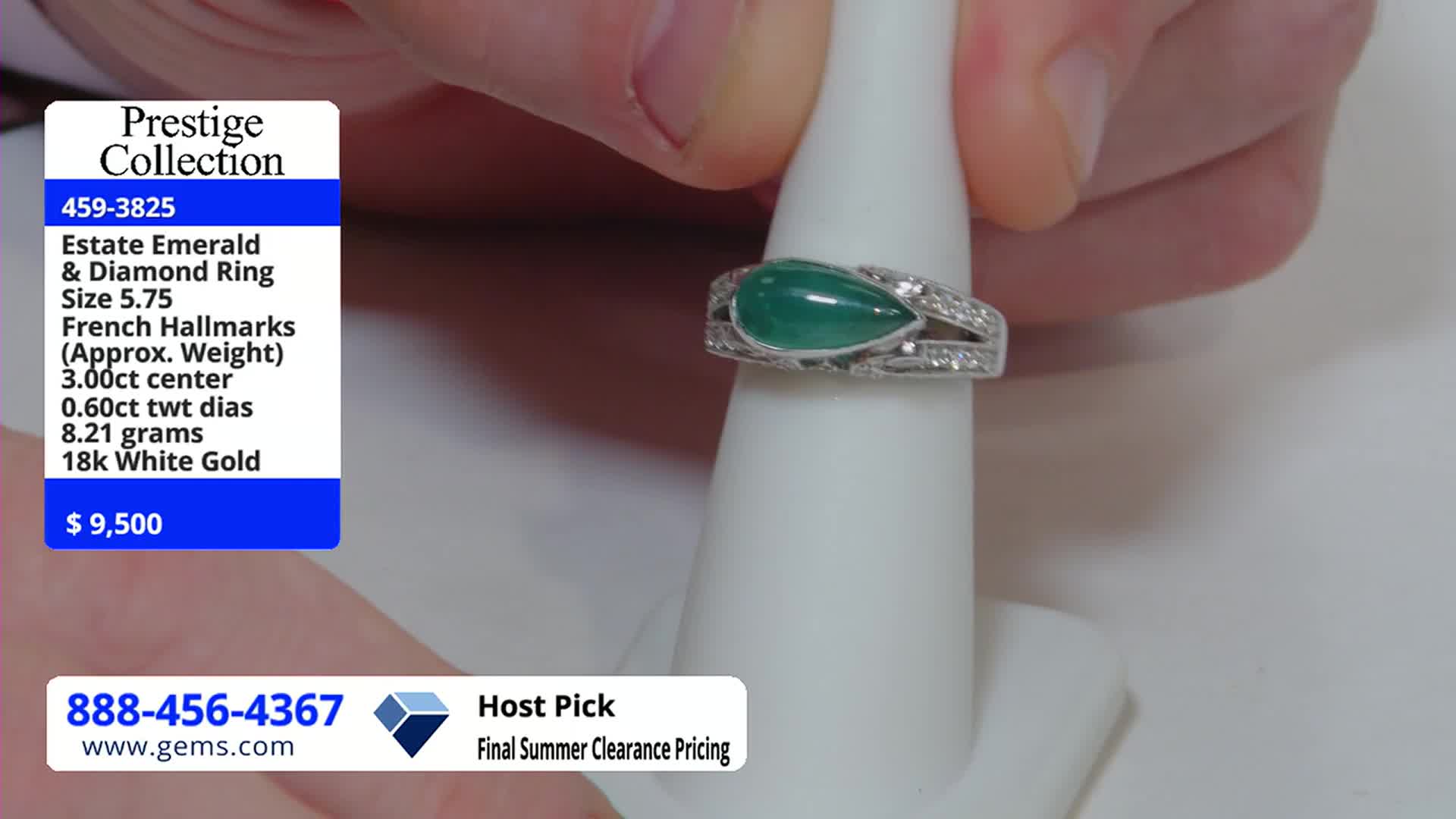 A hand holds a ring with a large, teardrop-shaped emerald, displaying it on a white stand. The Gem Shopping Network's price tag shows it's $9,500.
