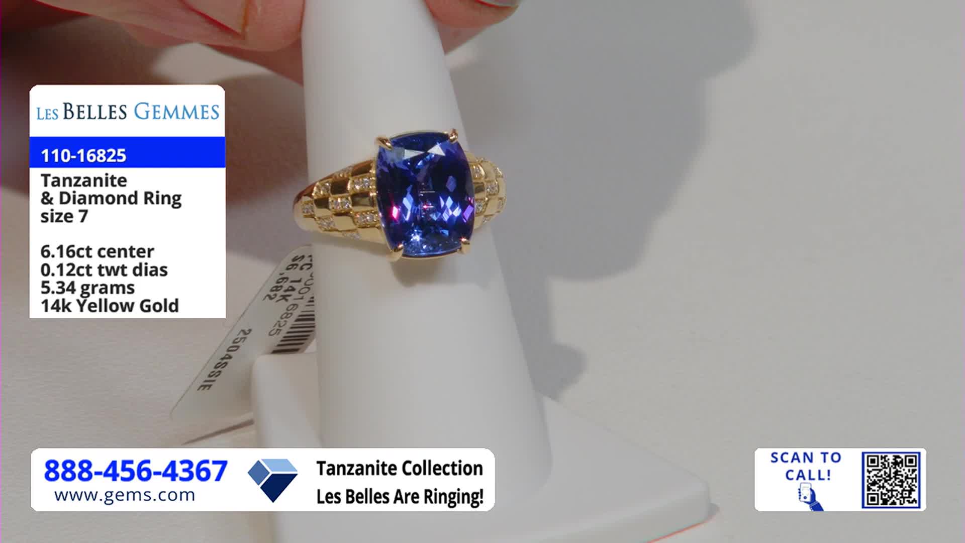 A hand holds a gold ring with a large, rectangular blue stone on a white display. The Gem Shopping Network logo and the ring's details are displayed in the corner.
