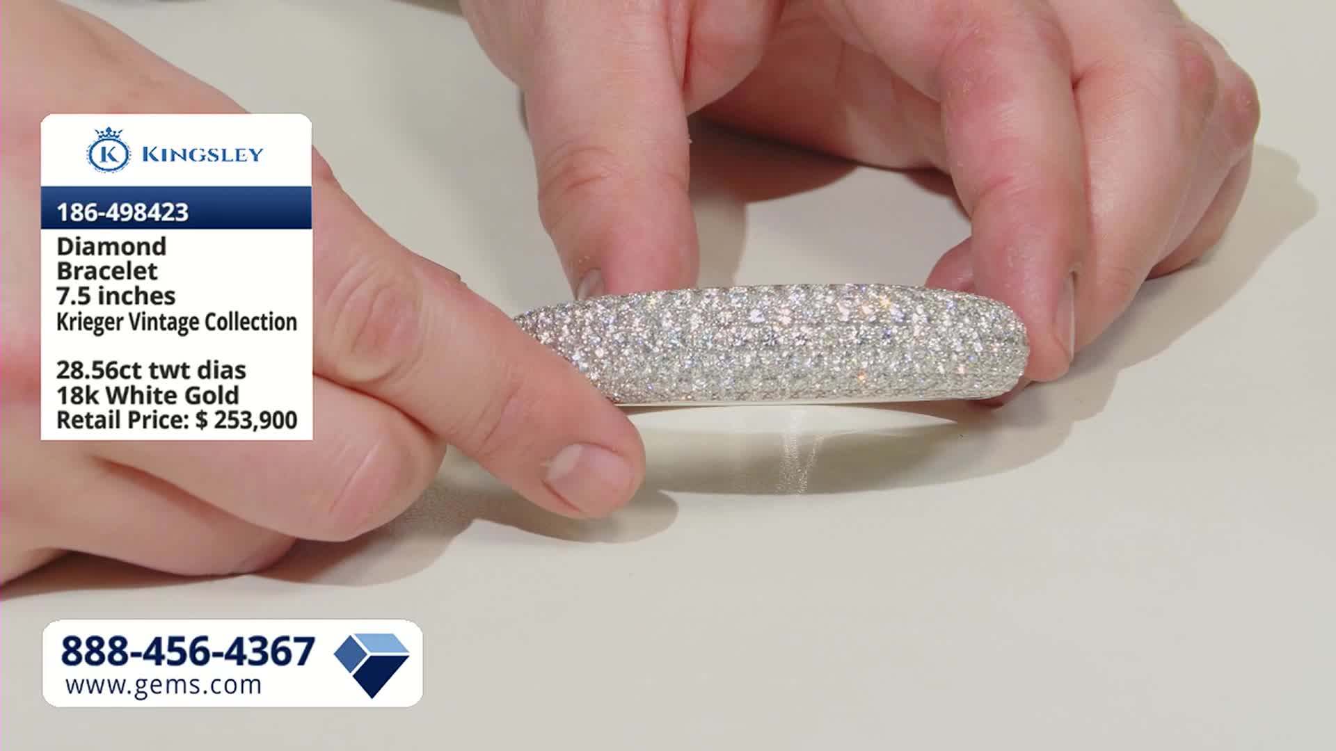 Fingers adjust a thick, curved bracelet covered in tiny, sparkling diamonds. This piece, a Krieger Vintage Collection item, is being presented on Gem Shopping Network.