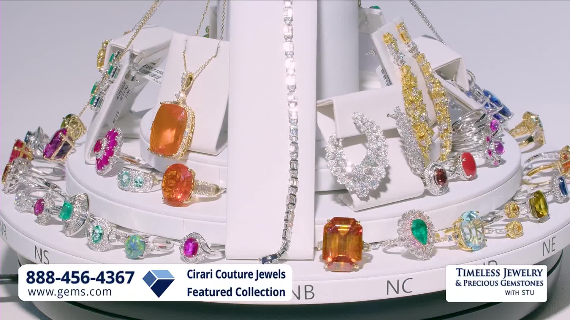 A display of rings, necklaces, and earrings with colorful gemstones rotates slowly. The Gem Shopping Network logo and a phone number are visible at the bottom.