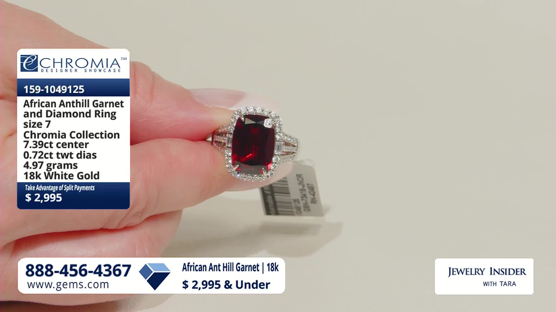 A hand displays a large, deep red garnet ring, its facets catching the light. The ring is surrounded by small, sparkling diamonds and set in white gold.