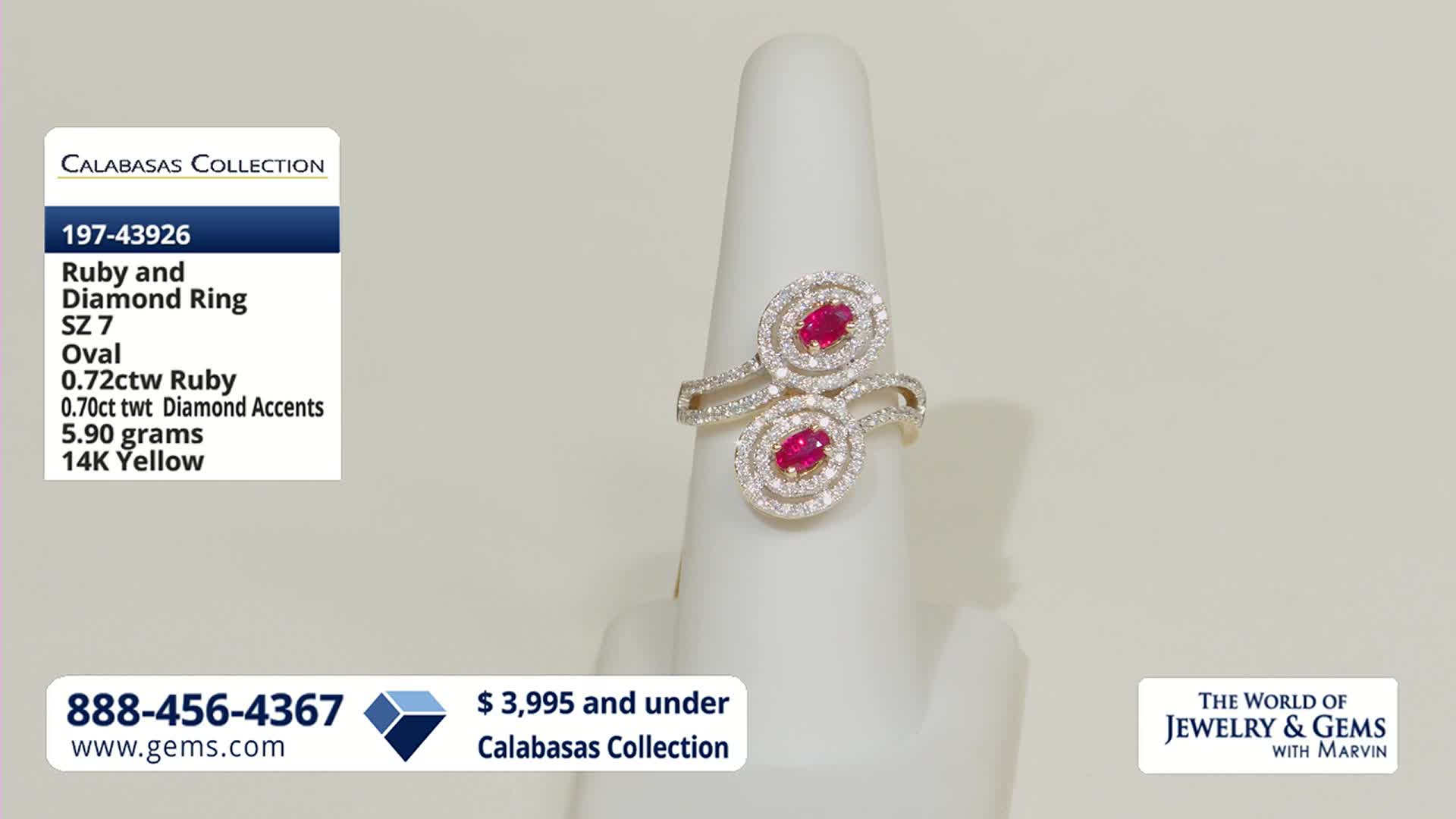 A white display stand holds a 14K yellow gold ring featuring two oval rubies surrounded by diamond accents. The ring's design twists, showcasing the gemstones prominently.