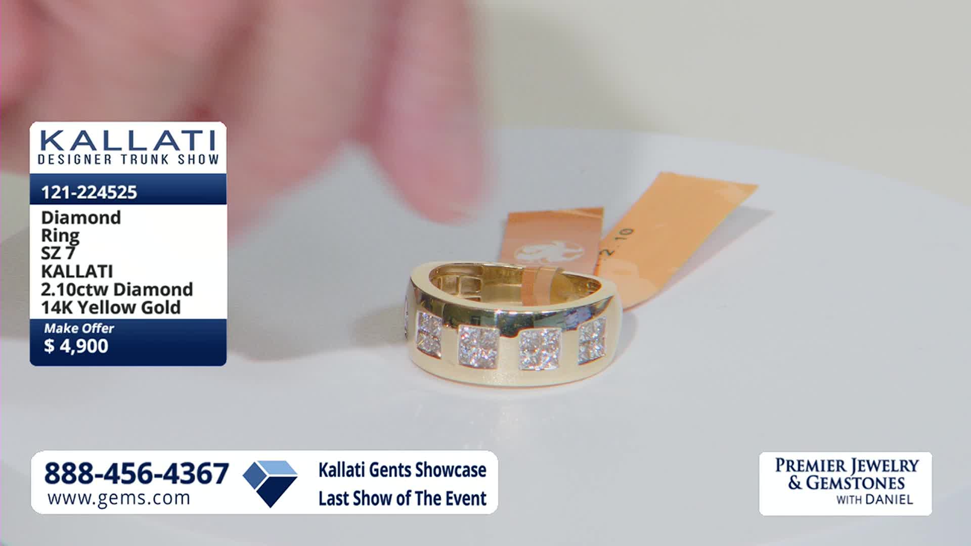 A hand hovers over a thick gold ring set with square-cut diamonds. Two orange tags sit behind the ring, one with writing on it.