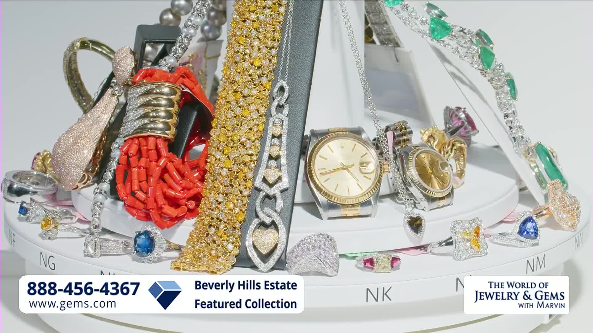 A display of dazzling jewelry, including diamond-encrusted watches and rings, sits on a rotating platform. A bright red coral necklace adds a pop of color to the opulent collection.