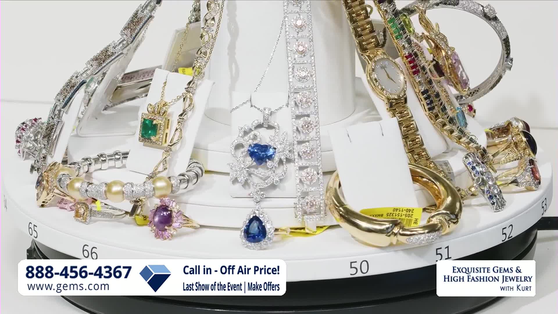 The jewelry display slowly rotates, showcasing a dazzling array of necklaces, bracelets, and rings. A prominent sapphire pendant dangles from a delicate chain, catching the light.