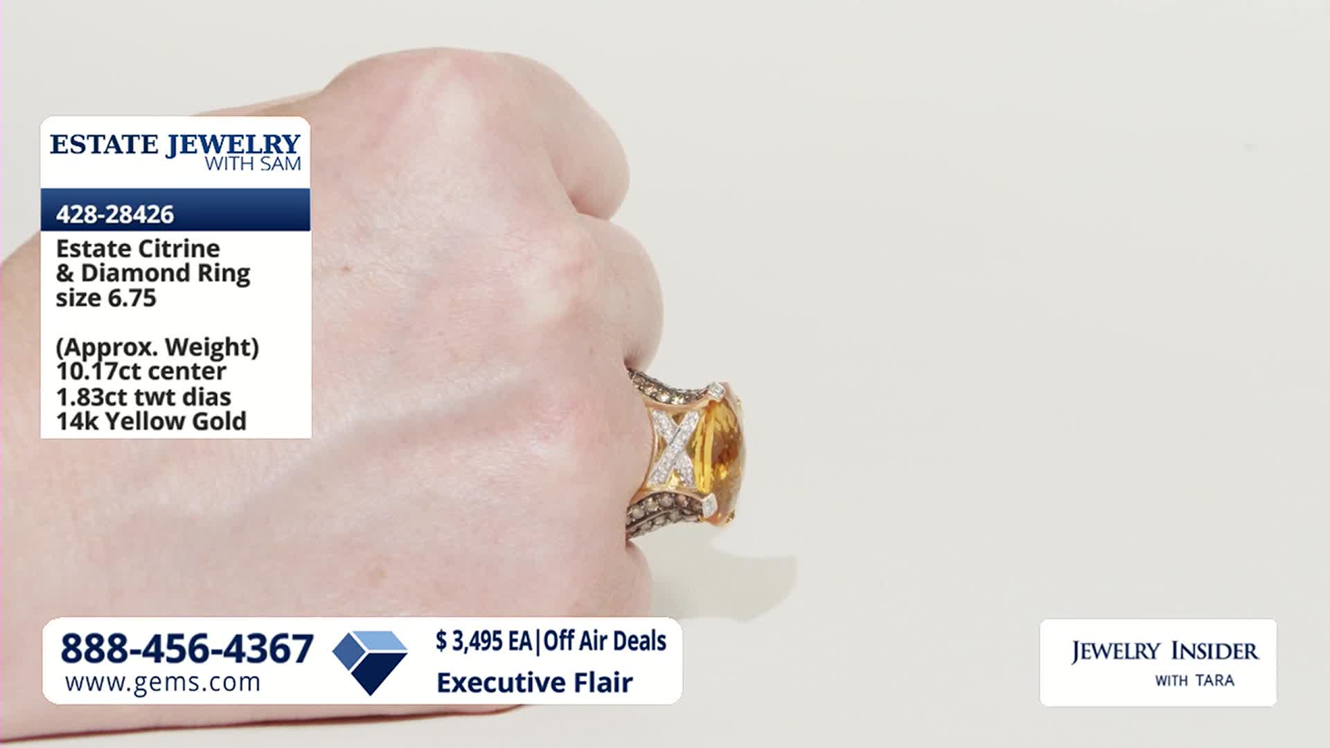 A hand turns, showcasing a large, oval citrine ring surrounded by diamonds. The ring's band is intricately detailed with smaller diamonds and gold.