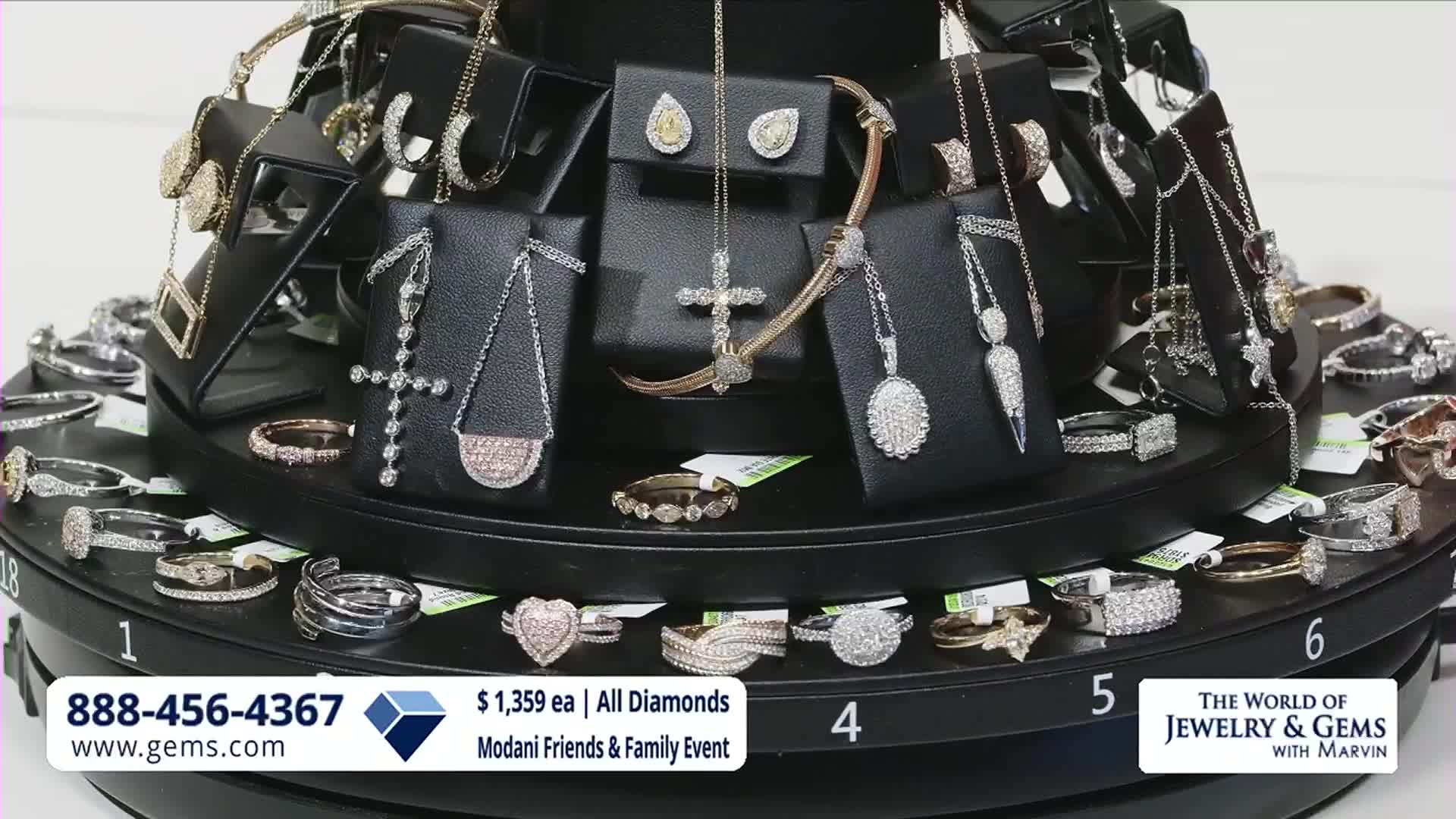 The jewelry display is slowly rotating, showcasing diamond necklaces and rings. A phone number and website for Gem Shopping Network flash at the bottom.