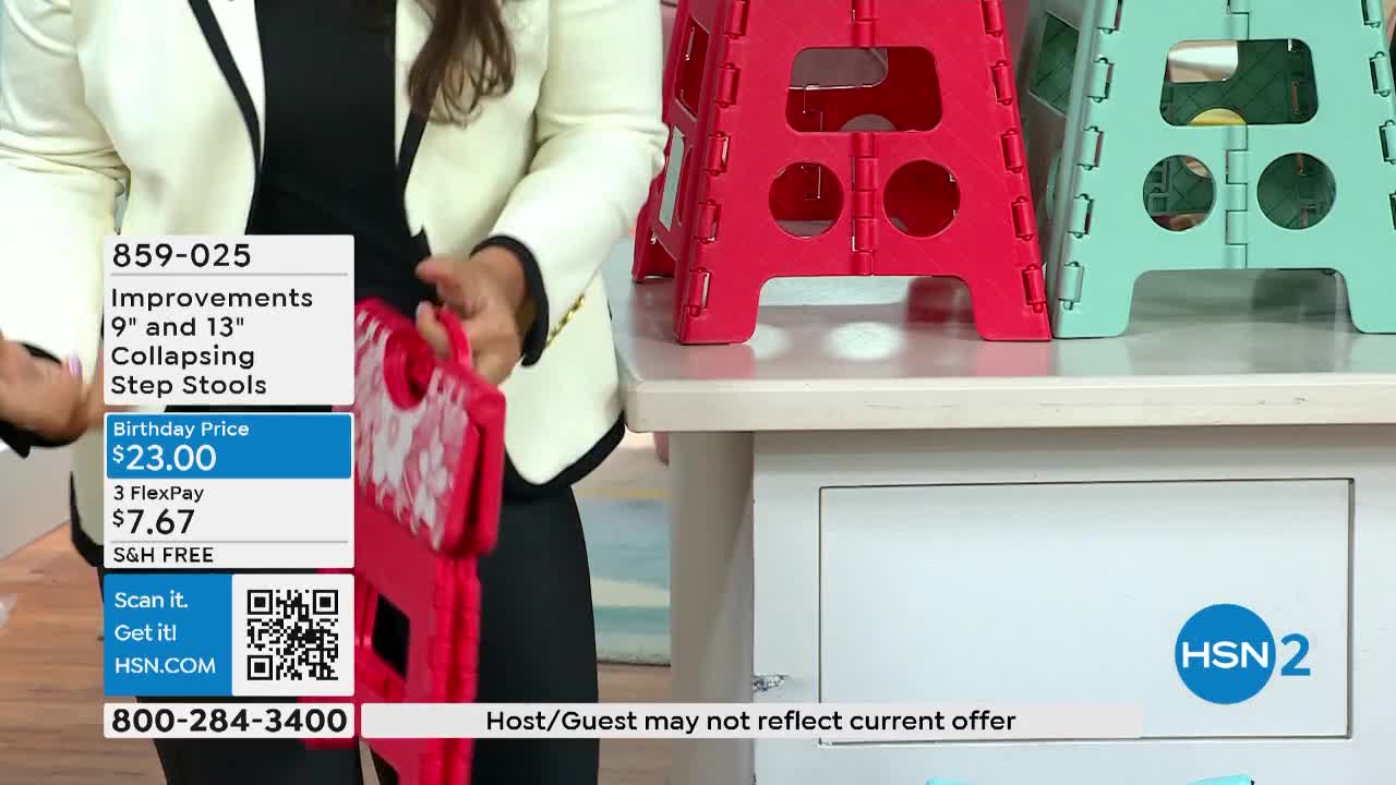 A woman in a blazer holds a folded red step stool, showing off its handle. Behind her, two more step stools, one red and one teal, sit open on a counter, and the HSN2 logo is visible.

