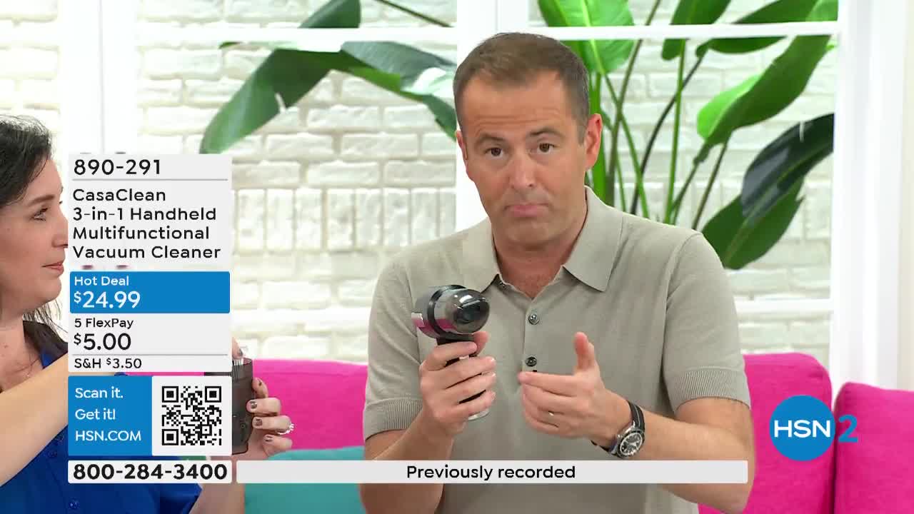 The man in the tan shirt holds up a small vacuum, gesturing with his other hand. A woman to his left displays a screen with the product's price and details.
