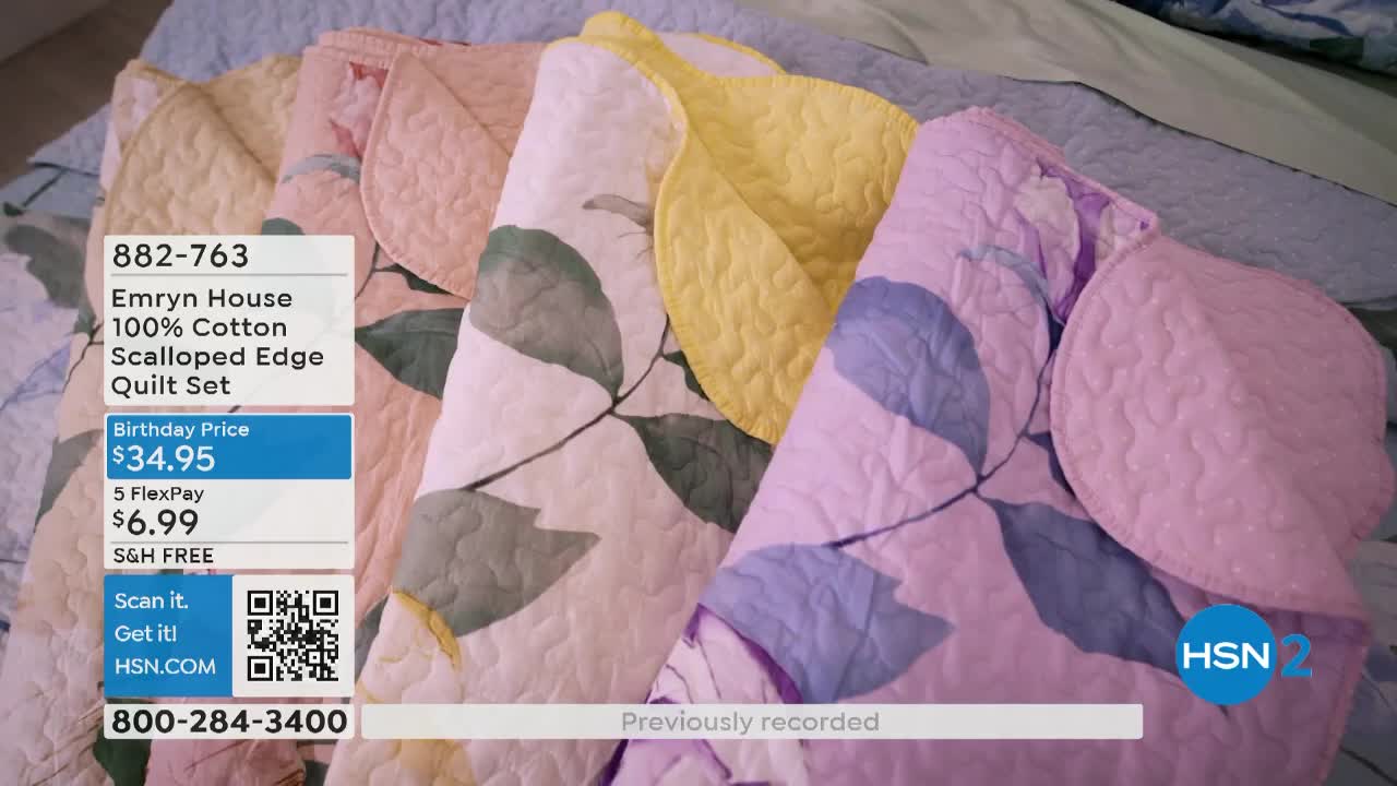 Scalloped-edge quilts in pastel colors are stacked, fanned out across a bed. The HSN2 logo and a product description are visible in the corner.
