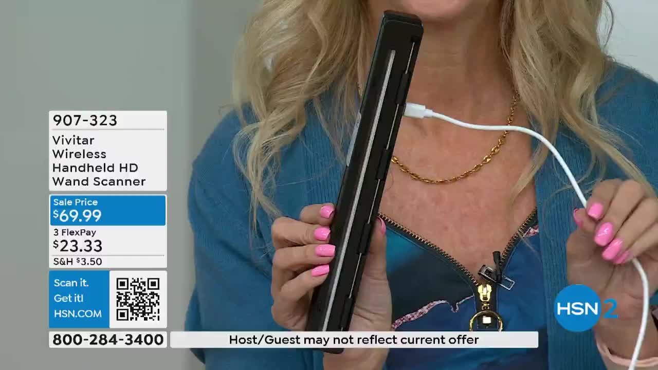 A woman holds a black, rectangular device, connected to a white cable. The HSN2 logo is visible, and the product's price is displayed on a screen.
