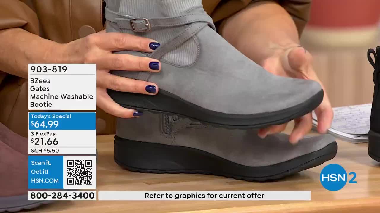 A woman holds a gray bootie, showing it off on HSN2. The shoe has a buckle, a black sole, and a price tag on the screen.
