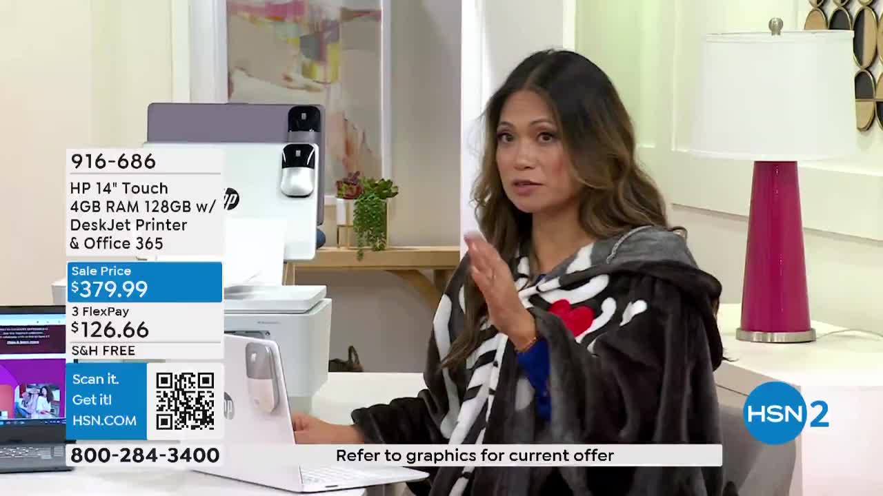 A woman, wrapped in a blanket, gestures with her right hand while speaking. Graphics display the sale price of a laptop and printer on HSN2.

