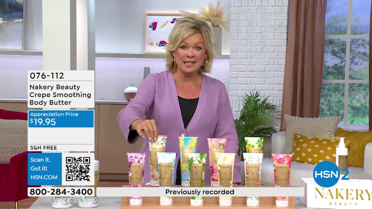 A woman in a purple sweater gestures toward a display of floral-patterned body butter tubes. The HSN2 host is presenting the product, and the price is prominently displayed on a screen.
