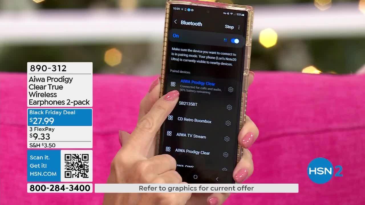 A hand with pink nails points to "AIWA Prodigy Clear" on a phone screen, which is connected to calls and audio. The HSN2 logo is visible in the bottom right corner.
