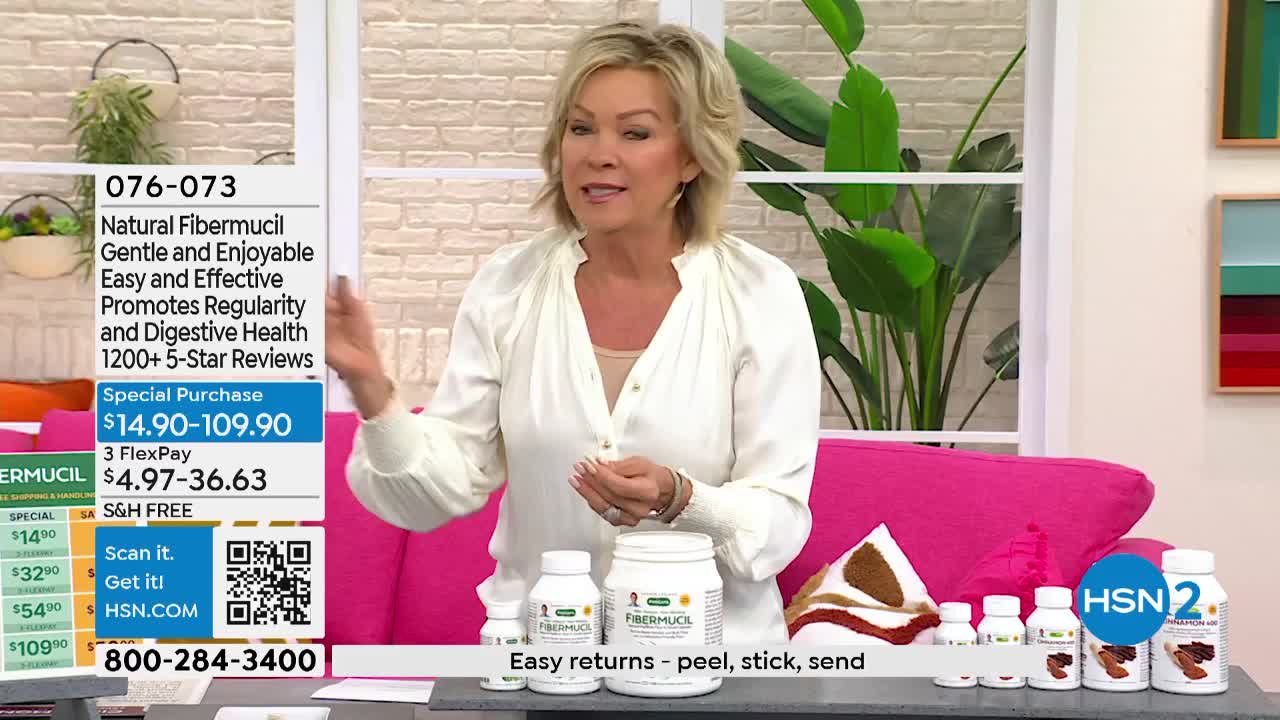 A woman in a white blouse gestures towards a display of Fibermucil products on a pink couch. The HSN2 logo is visible, and the screen shows a special offer.
