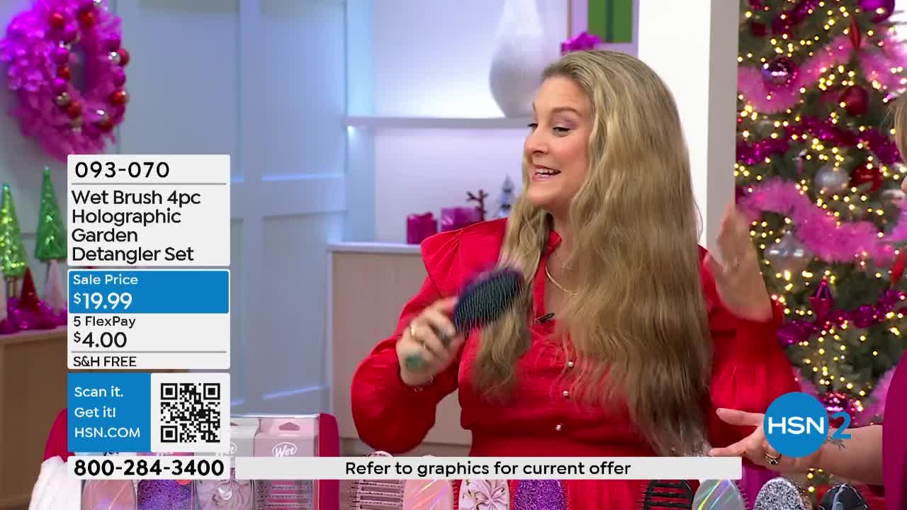 A woman in a red dress demonstrates a hairbrush, moving it through her long, blonde hair. The HSN2 backdrop includes a Christmas tree and product information.
