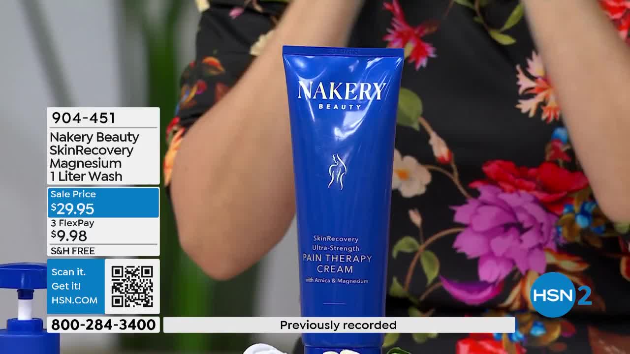 A woman's arm, adorned with a floral print sleeve, reaches for a large blue tube of Nakery Beauty Pain Therapy Cream. The product packaging displays "SkinRecovery Ultra-Strength" in bold lettering.