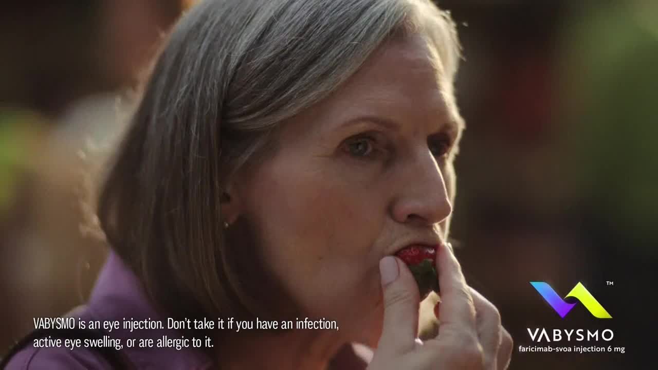 A woman with gray hair is about to bite into a ripe strawberry. The scene is bathed in soft, natural light, likely filmed in the United States for INSP.
