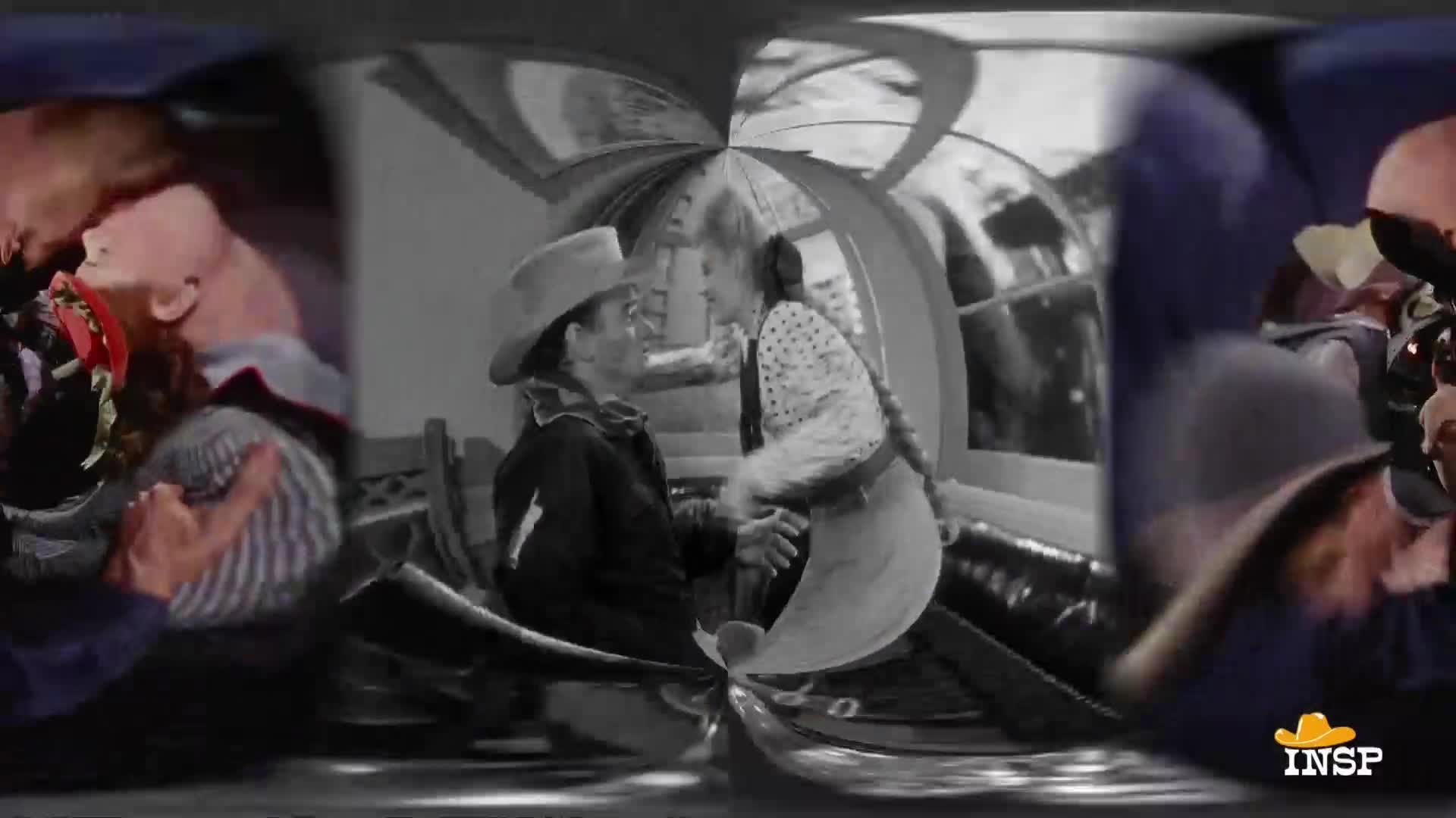 A man in a cowboy hat and a woman in a polka-dot dress lean in close to each other. They're about to kiss, framed by a window and a carriage interior.
