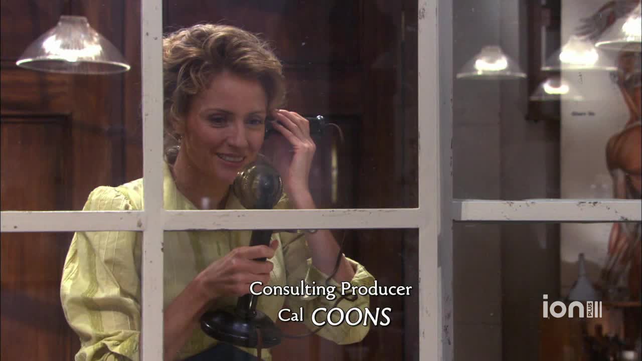 A woman in a pale yellow blouse holds a vintage telephone receiver to her ear, smiling. The scene is framed by a window, and the ION Plus logo is visible in the corner.
