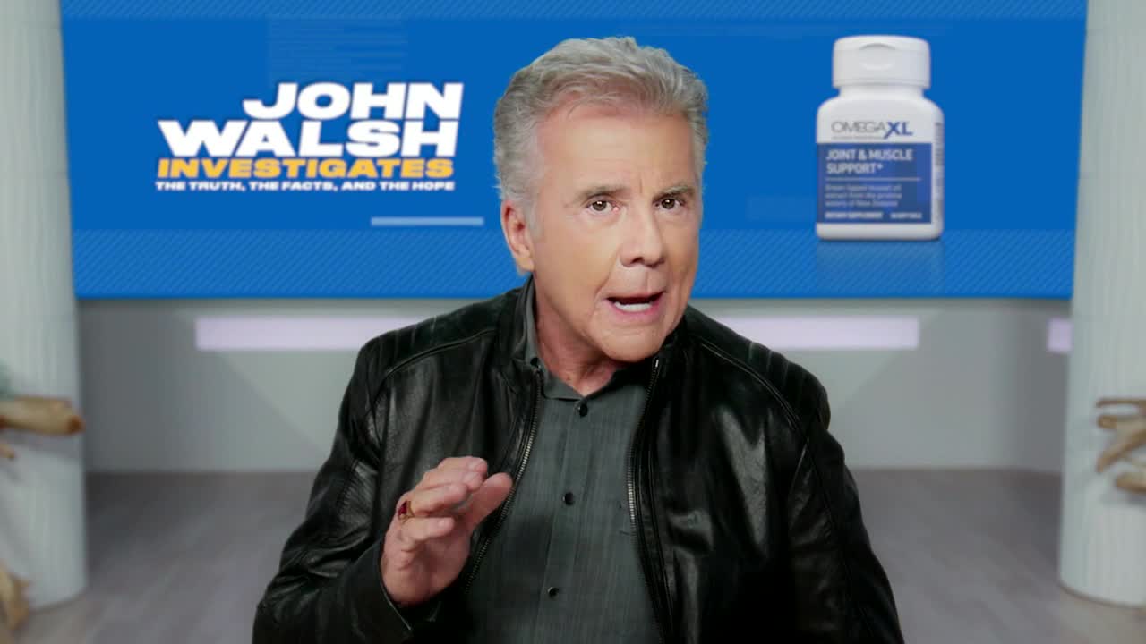 John Walsh, in a leather jacket, gestures with his right hand while speaking. Behind him, a blue backdrop displays the "John Walsh Investigates" logo and a bottle of OmegaXL.
