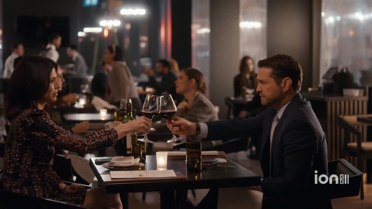 In a dimly lit restaurant, a man and woman raise their glasses in a toast. The ION Plus logo is visible in the corner of the screen.
