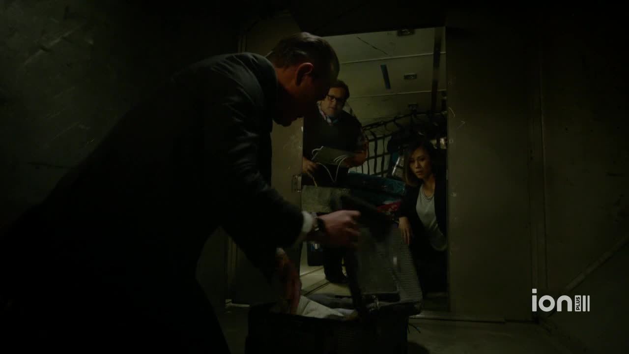 A man in a suit is rummaging through a suitcase, while two others watch from the doorway. The scene is dimly lit, with the ION Plus logo visible in the corner.
