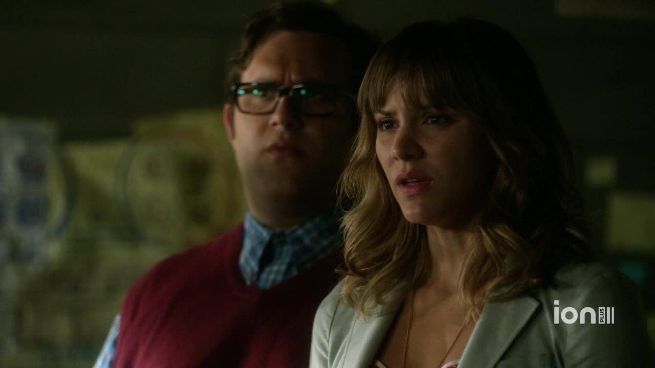 A man in glasses and a red sweater vest stares intently, while a woman beside him looks concerned. The ION Plus logo is visible in the corner.
