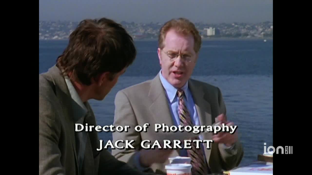 A man in a suit gestures with his hands while speaking to someone off-screen, the ocean visible behind them. The ION Plus logo is in the corner, and the credits for "Director of Photography" are displayed.
