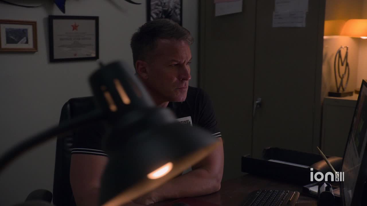 The man is hunched over a computer, his face illuminated by the glow of the screen and a desk lamp. He’s intently focused on something, brow furrowed, as the ION Plus logo subtly appears in the corner.
