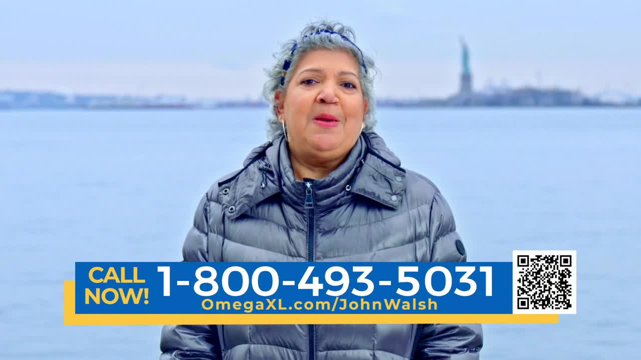 A woman in a puffy jacket stands in front of a body of water, the Statue of Liberty visible in the distance. A phone number and website address are displayed on a banner across the bottom of the screen.
