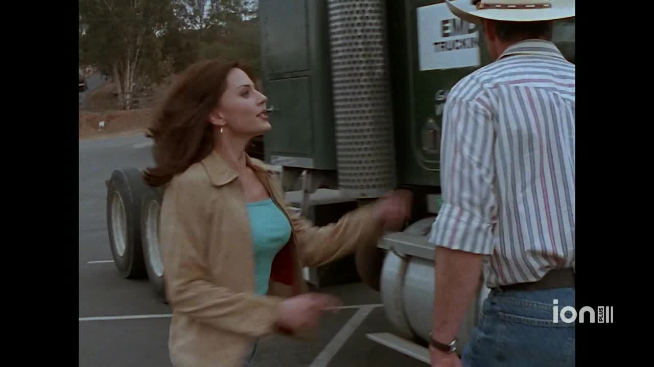 A woman in a tan jacket gestures emphatically toward a man in a cowboy hat next to a large truck. The scene is set outside, likely in the United States, and it's part of an ION Plus show.
