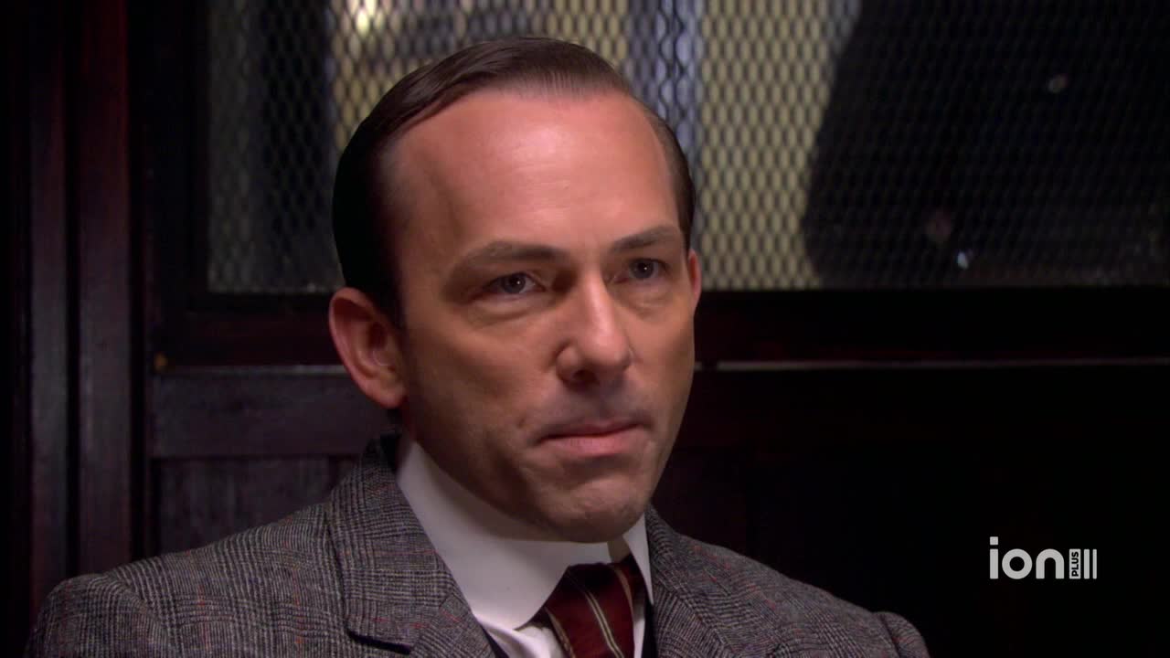 A man in a tweed jacket stares intently, his expression unreadable. The ION Plus logo sits in the corner, suggesting this is a scene from a show.
