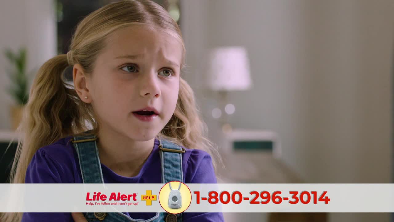 A young girl with blonde pigtails stares off-screen, her mouth slightly open. A Life Alert ad with a toll-free number is displayed at the bottom.
