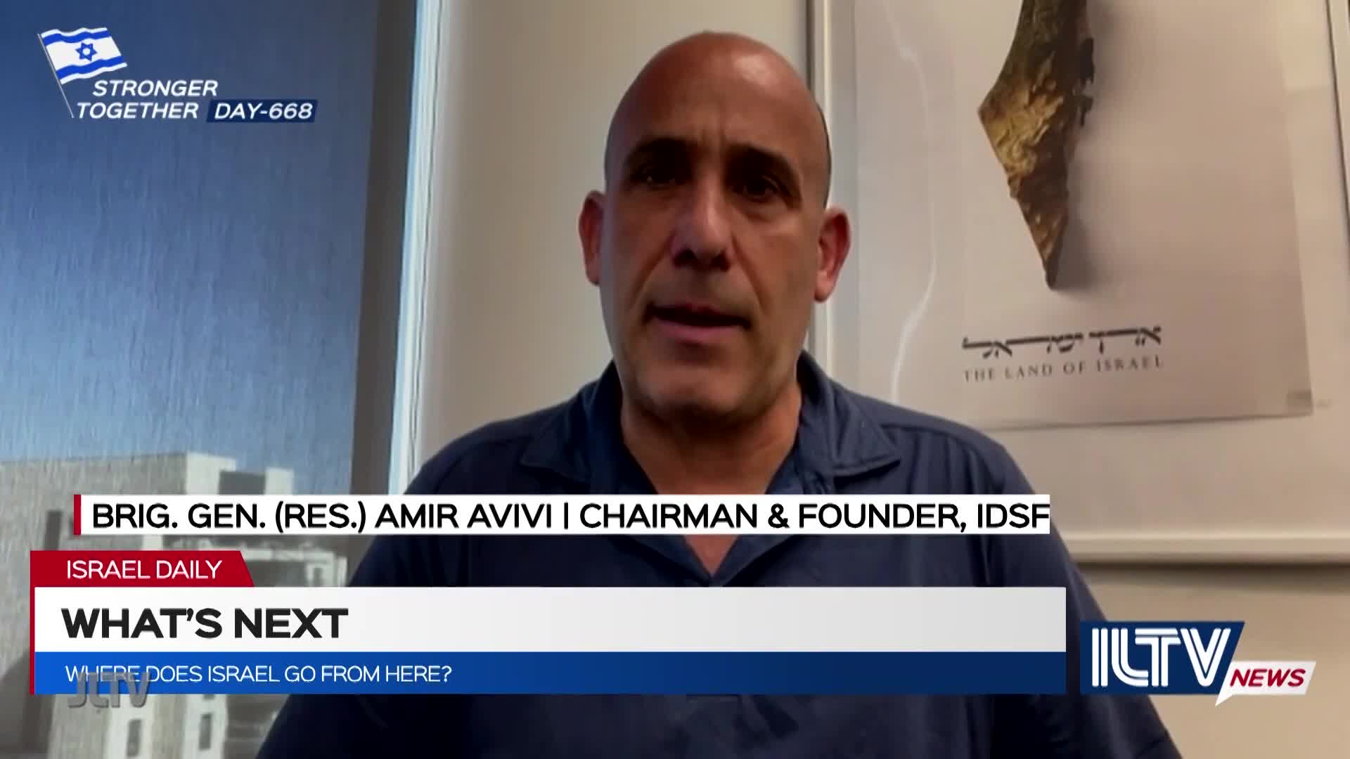 A man with a shaved head, identified as Amir Avivi, is speaking on ILTV News. Behind him, a framed map of Israel hangs on the wall.
