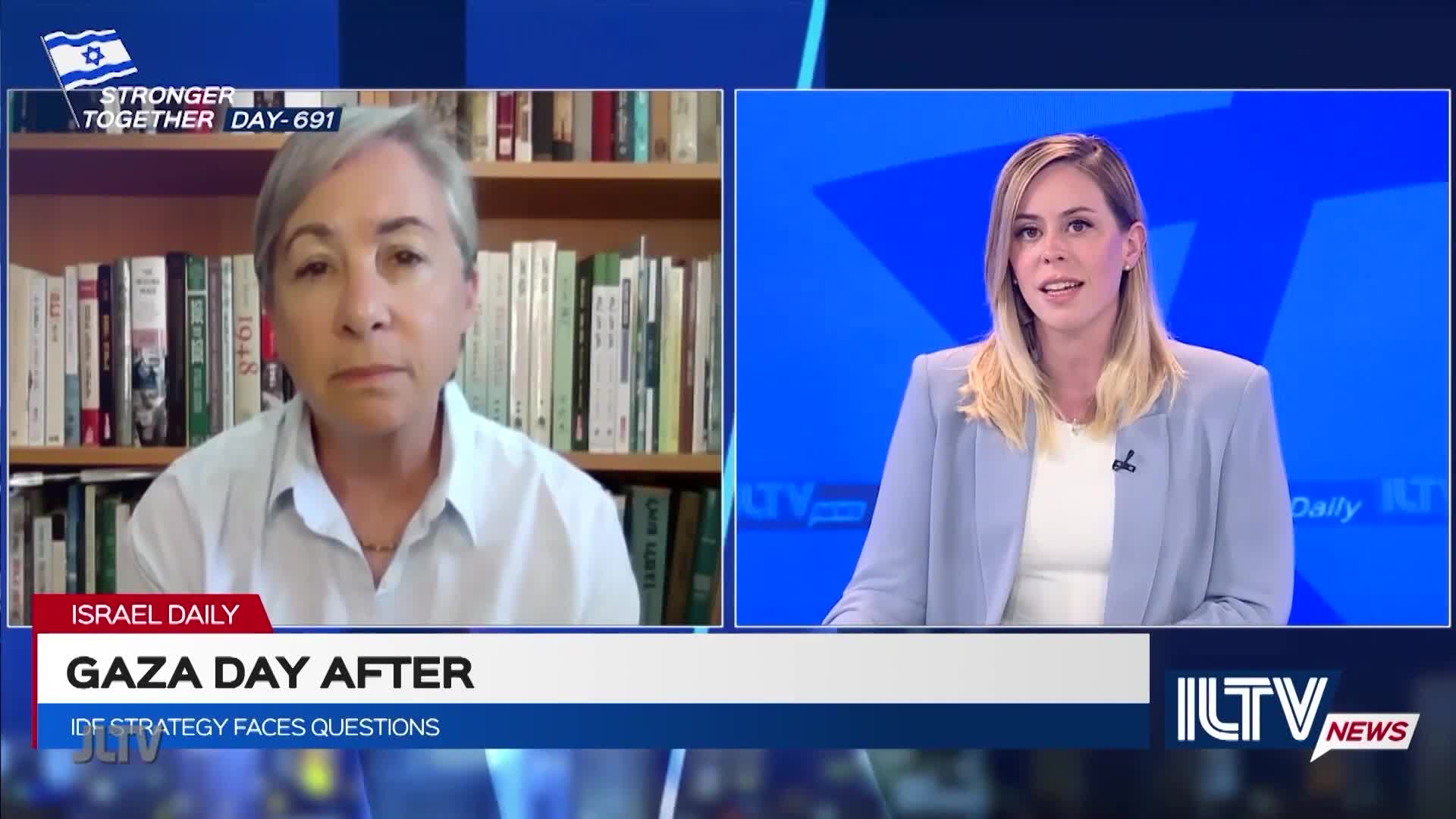 On Jewish Life Television, a woman with gray hair sits in front of a bookshelf, speaking. Across the screen, a news anchor in a blue blazer listens intently.
