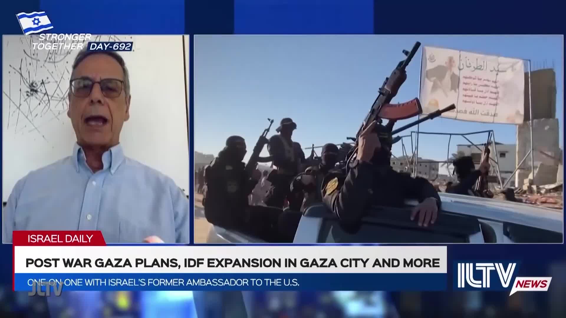 On Jewish Life Television, a man in glasses discusses post-war plans. The screen shows armed figures riding in a vehicle, with a banner in the background.
