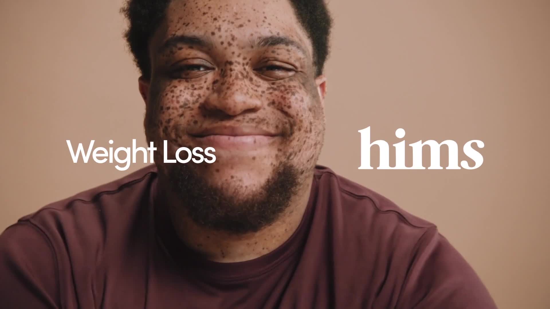 A man with freckles smiles directly at the camera, framed against a neutral background. The word "hims" is visible, alongside "Weight Loss," suggesting a product advertisement.
