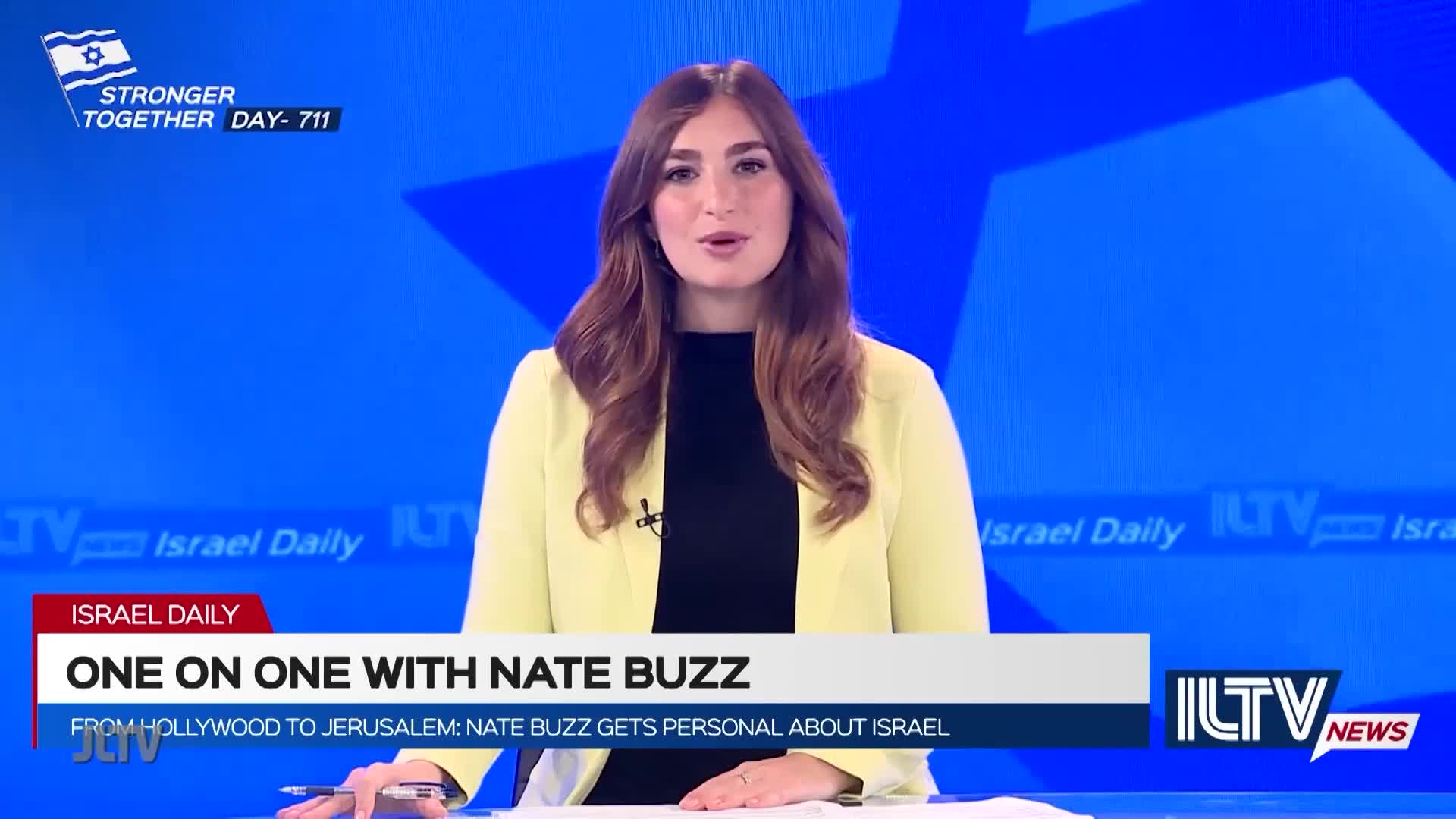A woman in a yellow blazer speaks directly to the camera, framed against a blue backdrop with the ILTV logo. The show, "One on One with Nate Buzz," is about to begin.
