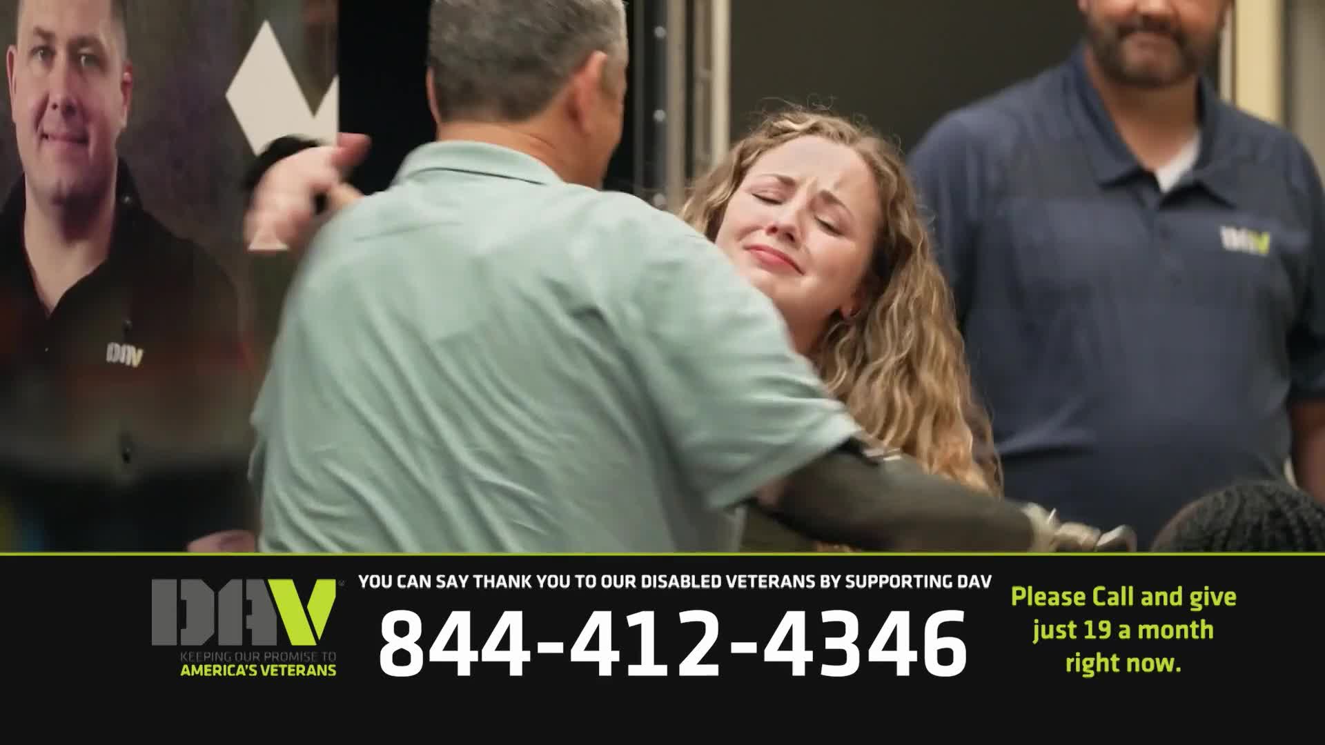 A woman, visibly emotional, is embraced by a man in a light green shirt. Behind them, a man in a blue shirt watches, as the screen promotes support for disabled veterans.

