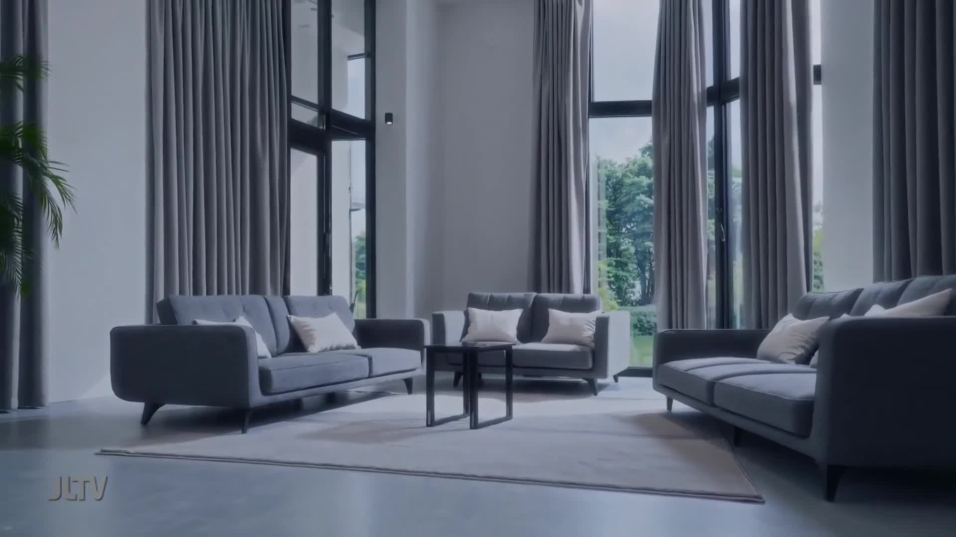 The JCTV logo appears in the lower left corner of this modern living room. Three gray sofas are arranged around a small black coffee table.
