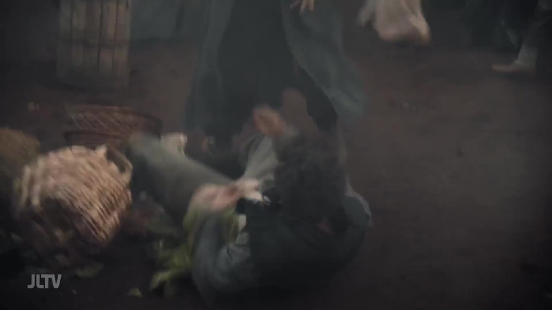 A person tumbles to the ground amidst scattered baskets and produce. Another figure, draped in dark fabric, moves quickly overhead.