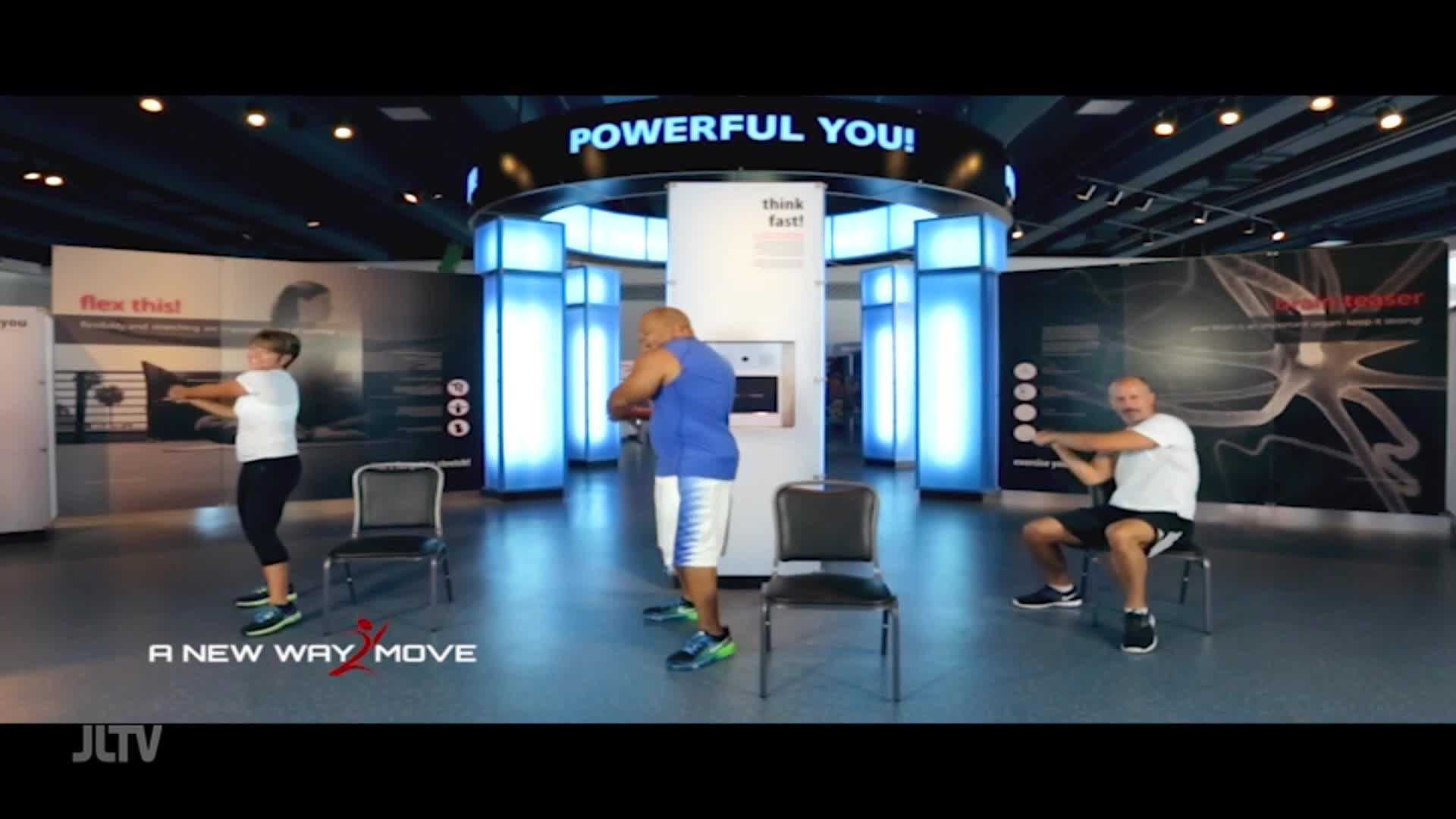 A woman in a white shirt and black leggings stands, twisting her torso. A man in a blue tank top and white shorts mirrors her movement, while another man in a white shirt and black shorts sits, extending his arms. The JLTV logo appears at the bottom left.