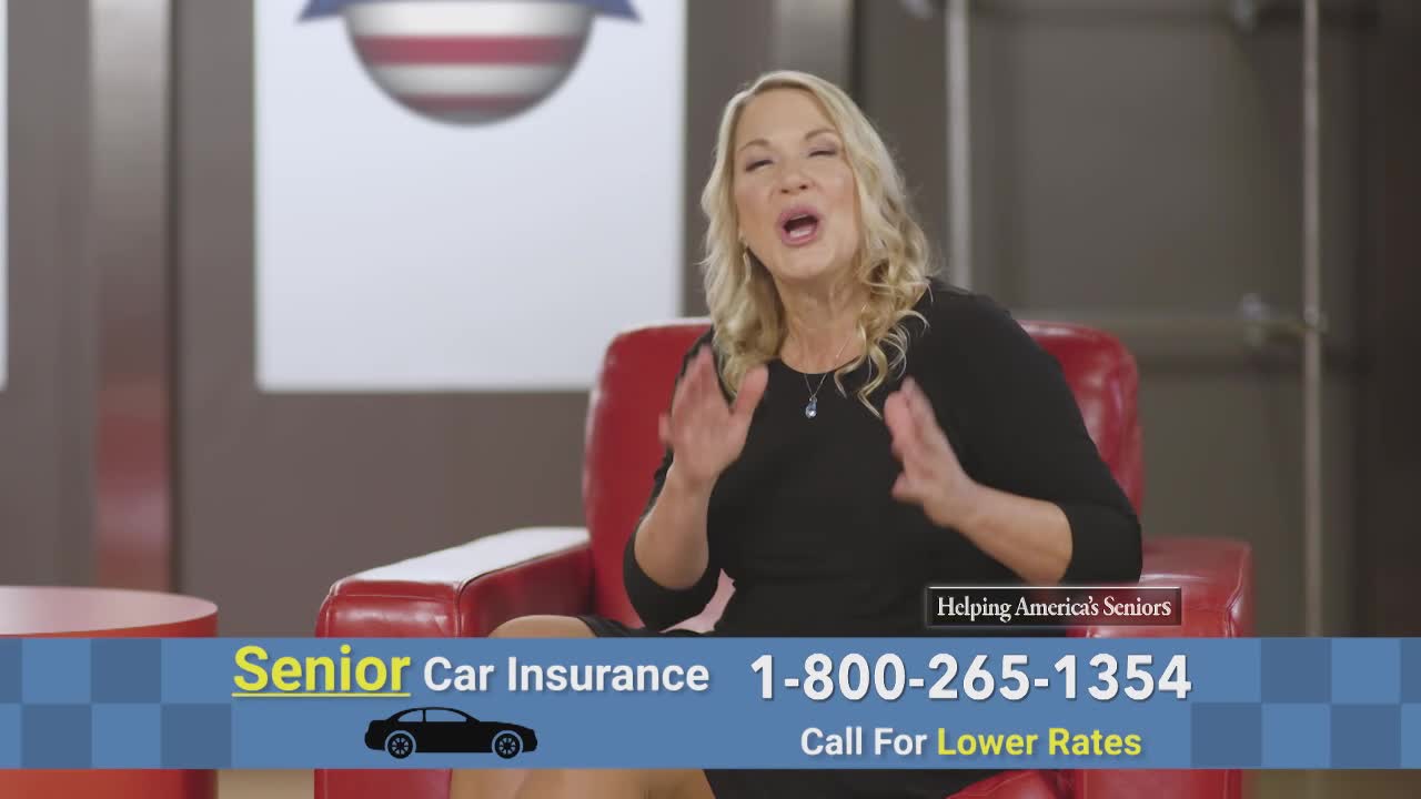 A woman in a black dress sits in a red chair, gesturing with her hands. The screen displays a phone number for senior car insurance, with an American flag graphic in the background.
