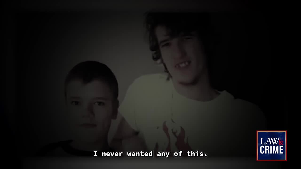 Two young men are framed in a dimly lit shot, one with a slightly crooked grin. Below them, the words "I never wanted any of this" appear, underscored by the Law & Crime logo.
