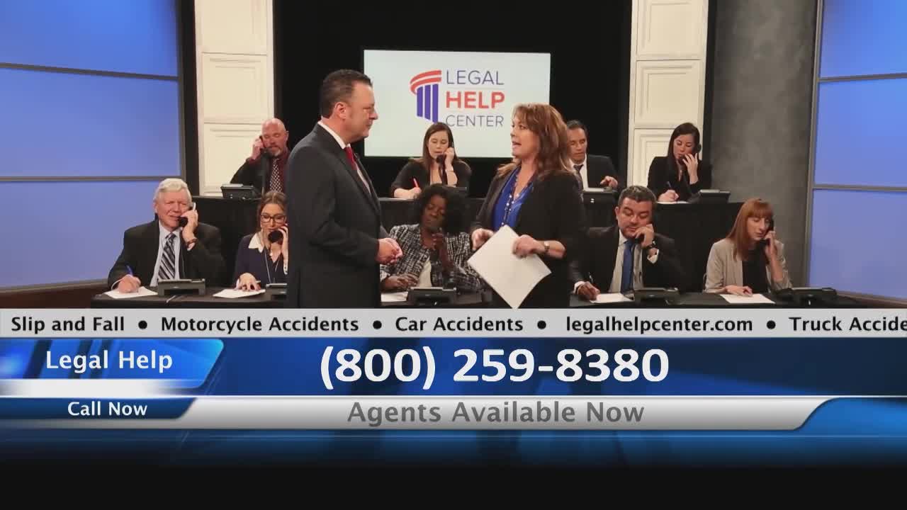 Two people in suits are talking in front of a backdrop, while a group of people behind them are on the phone. The screen displays a phone number for legal help.

