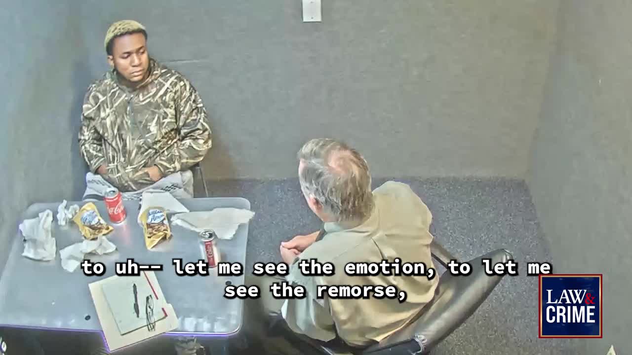 A man in camouflage sits across from another man, who leans forward in a chair. The table between them holds snacks and drinks, and the Law & Crime logo is visible.
