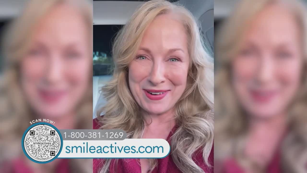 A woman with blonde hair smiles directly at the camera, speaking from inside a car. A graphic for "Smileactives" and a phone number appears at the bottom of the screen.
